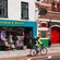 A helmeted bicyclist rides down a street near a shop with a sign that reads Records and Relics